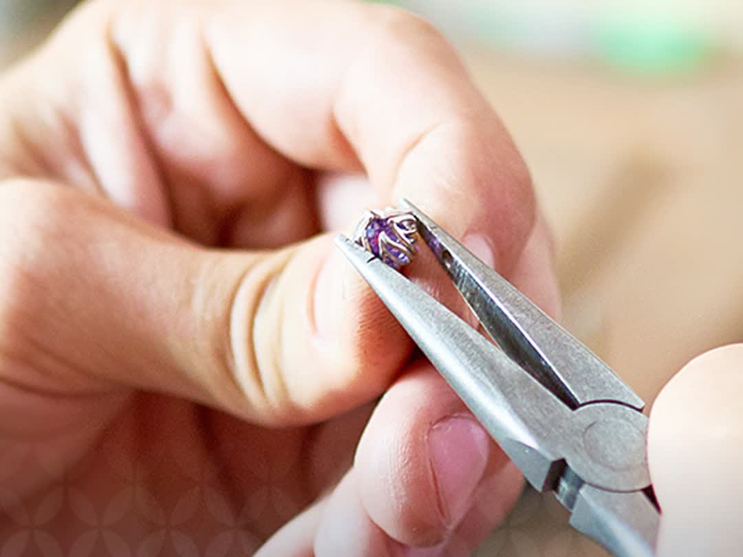 Mãos a segurar uma gema preciosa com pinça — curadoria
